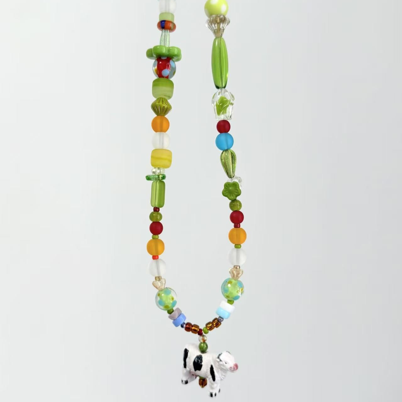 Colorful beaded necklace with a cow pendant on a white background