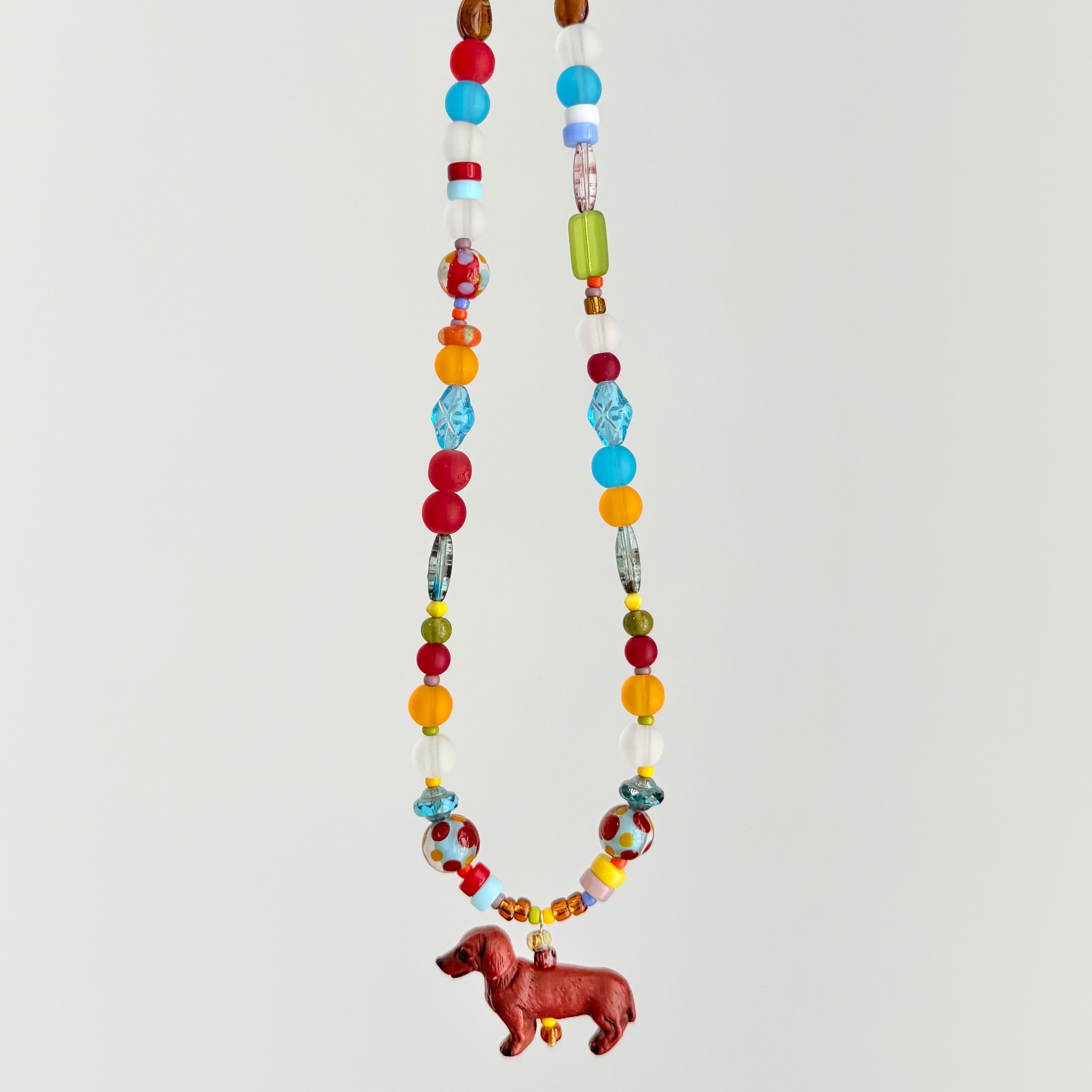 Colorful beaded necklace with a small dog charm on a light gray background