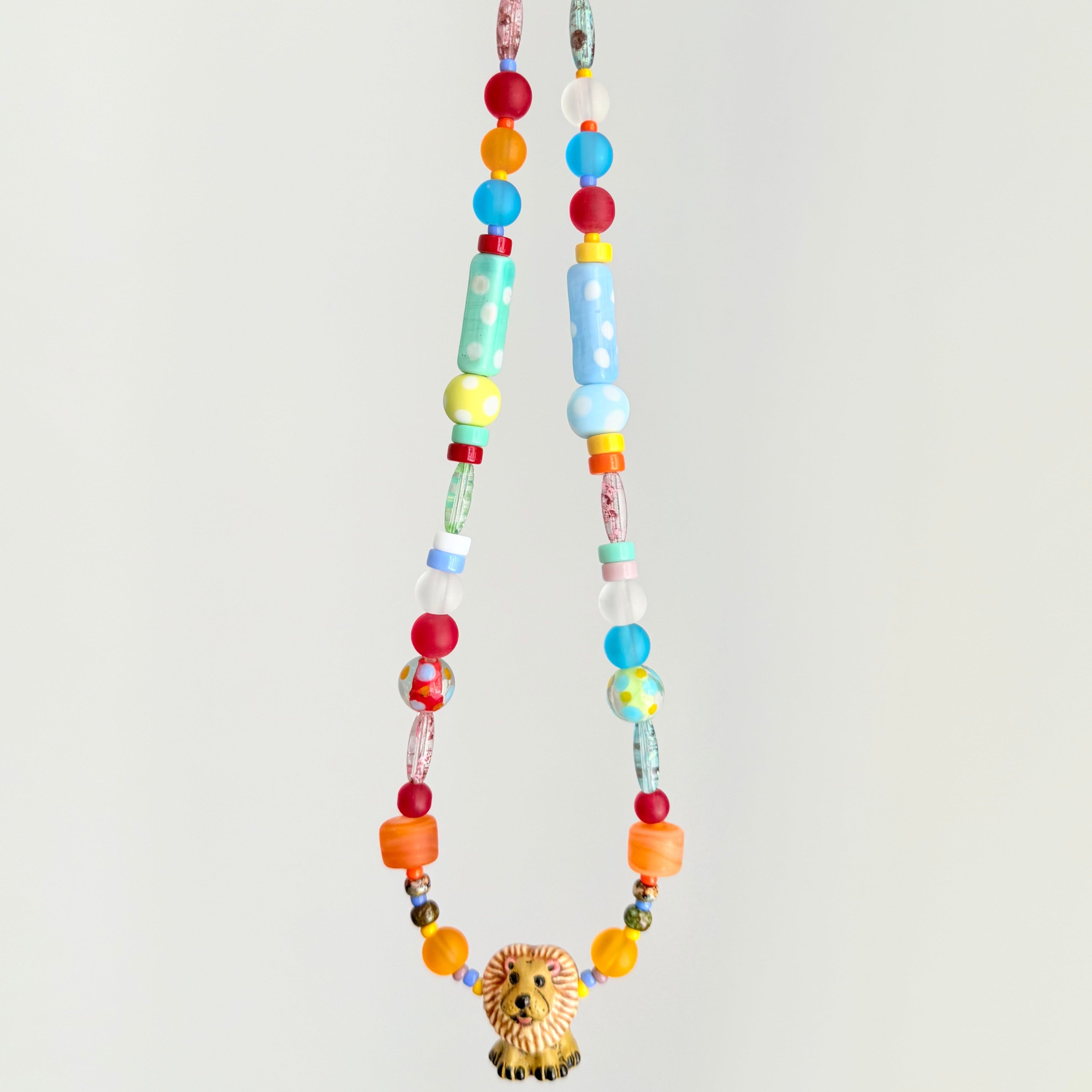 Colorful beaded necklace with a lion pendant on a light gray background
